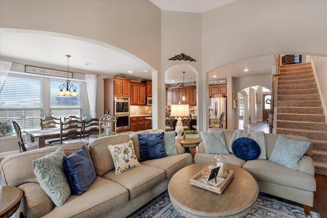 living room featuring recessed lighting, a high ceiling, an inviting chandelier, arched walkways, and stairs