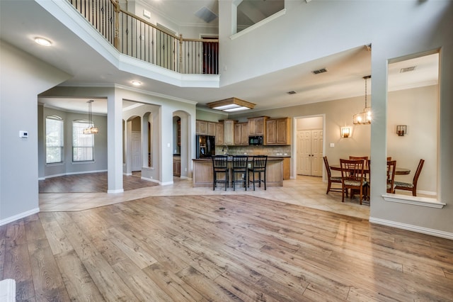 103 Lakehill Ct, Hickory Creek, TX 75065 - living room with a high ceiling, baseboards, crown molding, light wood-style flooring, and a chandelier