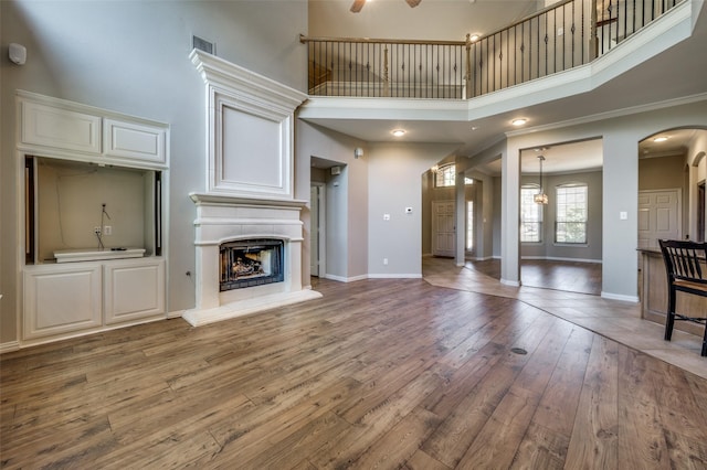 103 Lakehill Ct, Hickory Creek, TX 75065 - unfurnished living room with a high ceiling, hardwood / wood-style flooring, a fireplace with raised hearth, baseboards, and ornamental molding