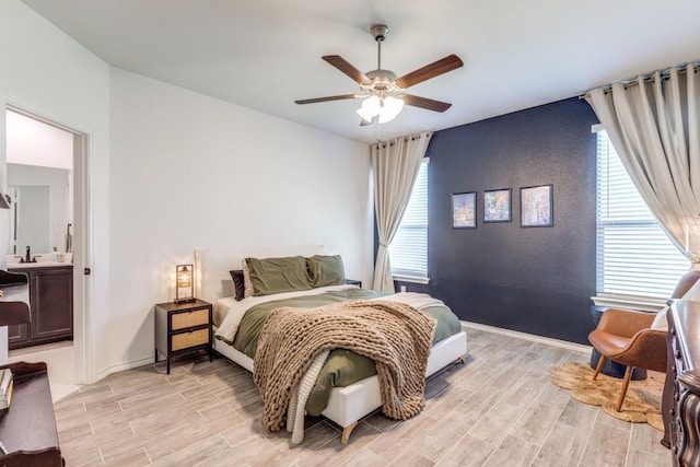 bedroom with a ceiling fan, baseboards, an accent wall, and light wood finished floors