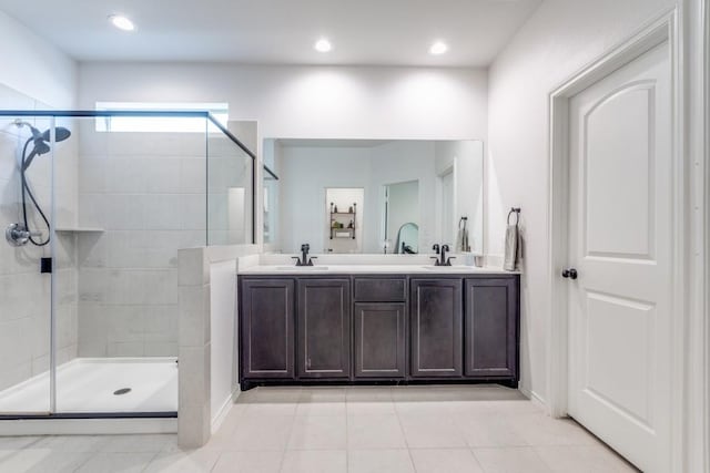 bathroom featuring tile patterned floors, a sink, double vanity, and a tile shower