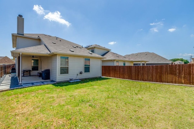 back of house featuring a chimney, a lawn, a fenced backyard, a patio, and ceiling fan