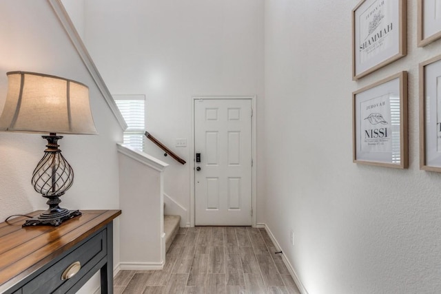 entryway with light wood-style flooring, baseboards, and stairway