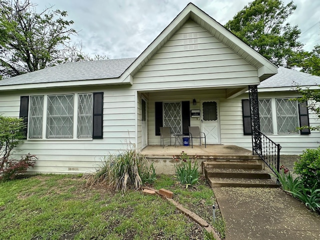 view of front facade with roof with shingles and a porch