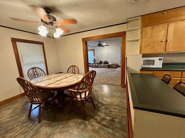 dining space with a ceiling fan, baseboards, and concrete flooring