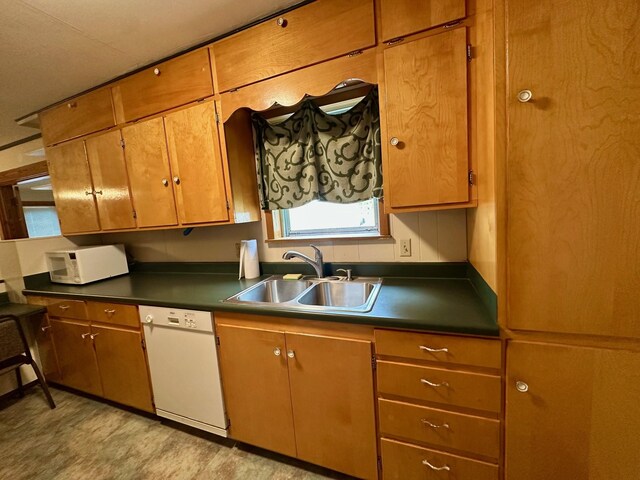 kitchen featuring white gas range oven, under cabinet range hood, brown cabinets, and dark countertops