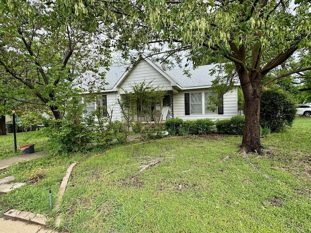 ranch-style home with roof with shingles and a front yard