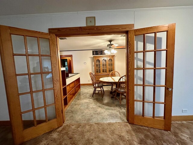 carpeted dining area featuring a ceiling fan, baseboards, and crown molding