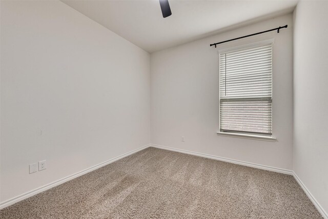carpeted spare room with a healthy amount of sunlight, a ceiling fan, and baseboards