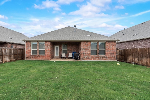 rear view of property featuring a fenced backyard, brick siding, and a yard