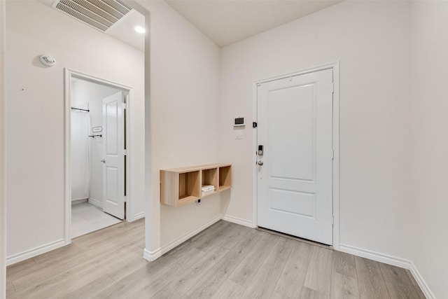 foyer with light wood-style floors, visible vents, and baseboards