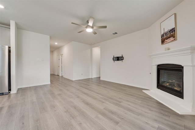 unfurnished living room with a ceiling fan, a glass covered fireplace, light wood-style floors, visible vents, and recessed lighting