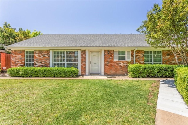 single story home featuring brick siding, a shingled roof, and a front lawn