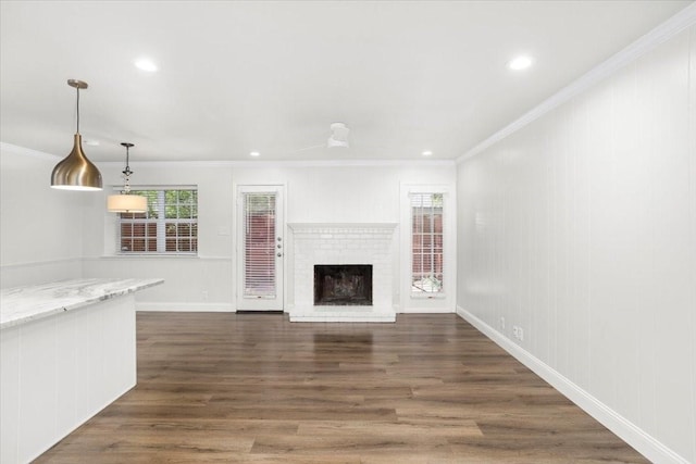 unfurnished living room with recessed lighting, dark wood-style flooring, ornamental molding, and a fireplace