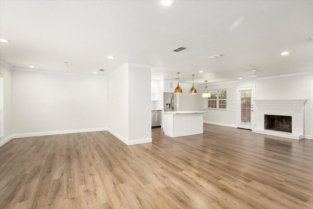unfurnished living room featuring a fireplace, crown molding, wood finished floors, and recessed lighting