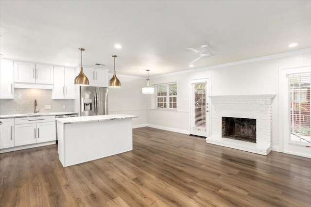kitchen with white cabinets, a center island, a sink, crown molding, and stainless steel refrigerator with ice dispenser