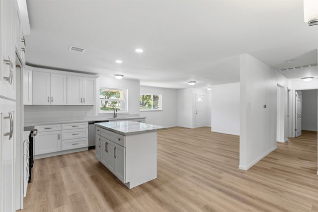7009 Overhill Rd, Fort Worth, TX 76116 - kitchen with light wood finished floors, visible vents, stainless steel dishwasher, a center island, and white cabinetry