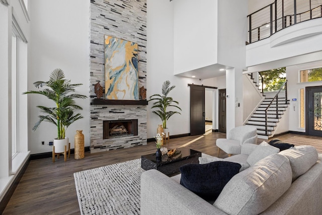 living area with a towering ceiling, wood finished floors, stairs, and a barn door