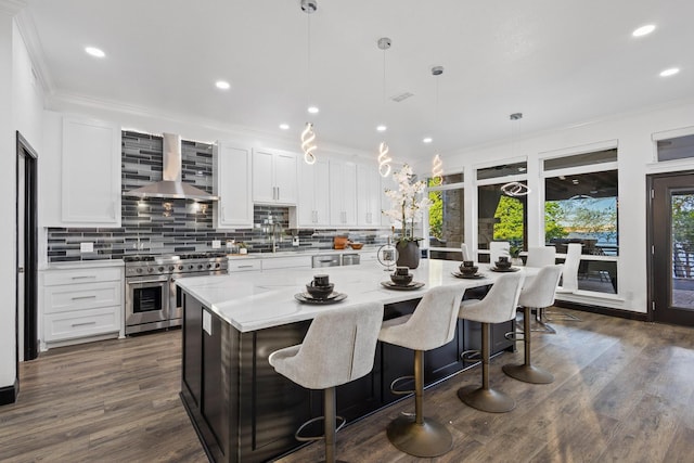 kitchen with white cabinets, wall chimney range hood, a center island, decorative backsplash, and range with two ovens