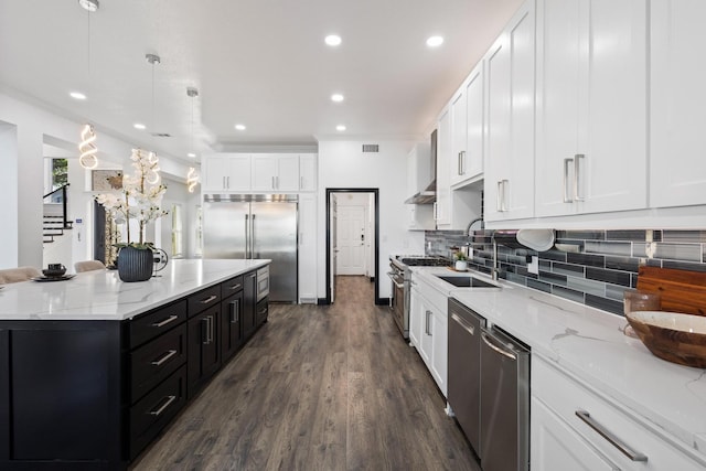 kitchen featuring dark wood-style floors, premium appliances, dark cabinets, a sink, and white cabinetry