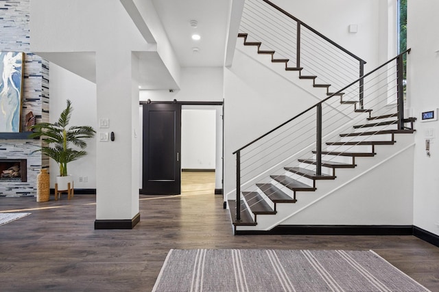 stairs with a barn door, baseboards, a towering ceiling, and wood finished floors