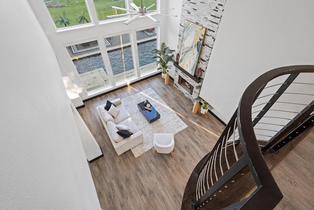 living area with ceiling fan, wood finished floors, and a water view