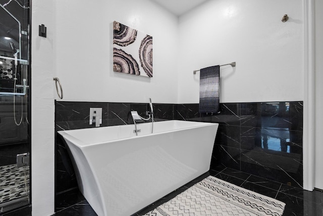 full bath featuring a freestanding bath, tile walls, and a wainscoted wall