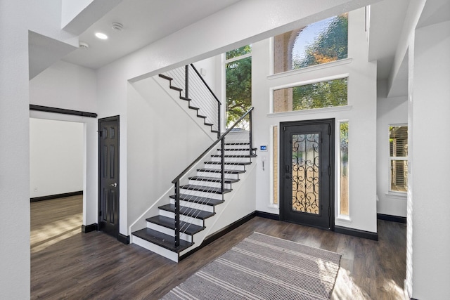 entryway with a towering ceiling, baseboards, recessed lighting, stairway, and dark wood-type flooring