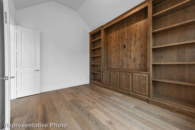 unfurnished bedroom with vaulted ceiling, wood finished floors, and a closet