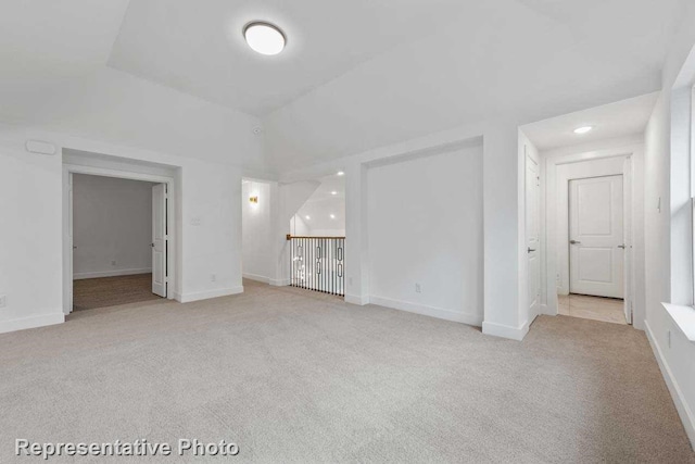 unfurnished living room featuring vaulted ceiling, baseboards, recessed lighting, and light colored carpet