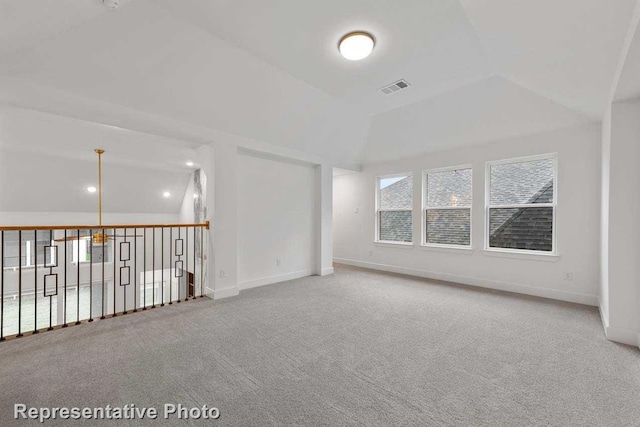 spare room with vaulted ceiling, visible vents, baseboards, and carpet
