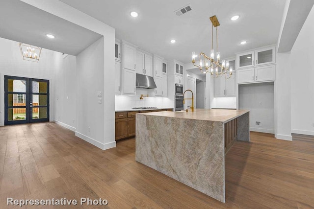 kitchen with baseboards, under cabinet range hood, and an inviting chandelier