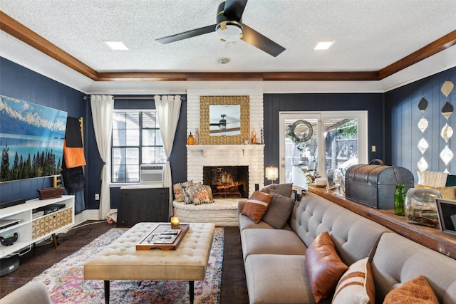 living area featuring a ceiling fan, ornamental molding, a textured ceiling, and a fireplace