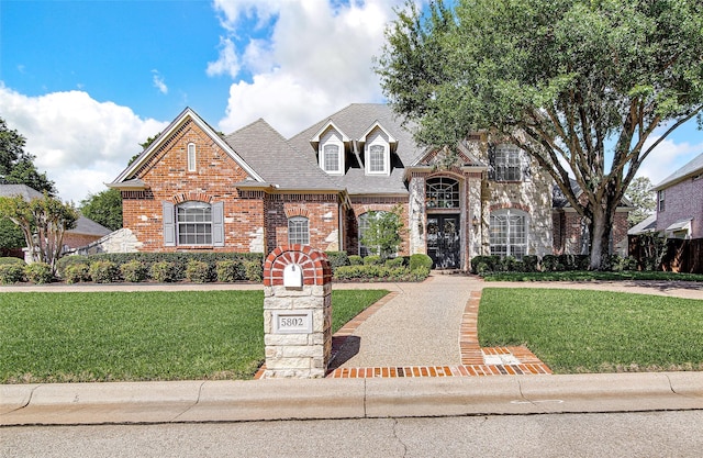 traditional-style home with a front lawn, brick siding, and a shingled roof