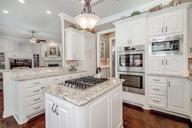 kitchen featuring stainless steel appliances, a ceiling fan, a center island, a peninsula, and white cabinetry