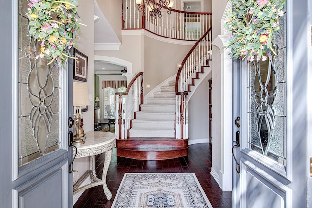 foyer entrance with stairway, dark wood-style flooring, ornamental molding, and baseboards