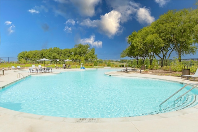 community pool featuring fence and a patio
