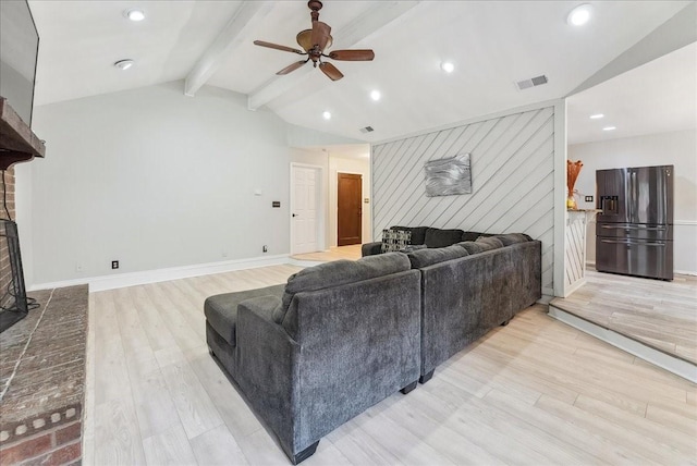 living room with vaulted ceiling with beams, ceiling fan, a brick fireplace, and light wood finished floors