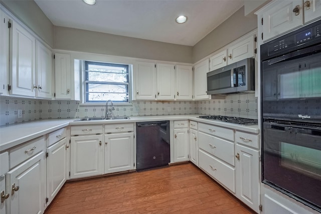 kitchen with a sink, white cabinets, and black appliances