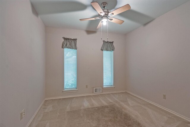 empty room featuring a ceiling fan, baseboards, visible vents, and carpet