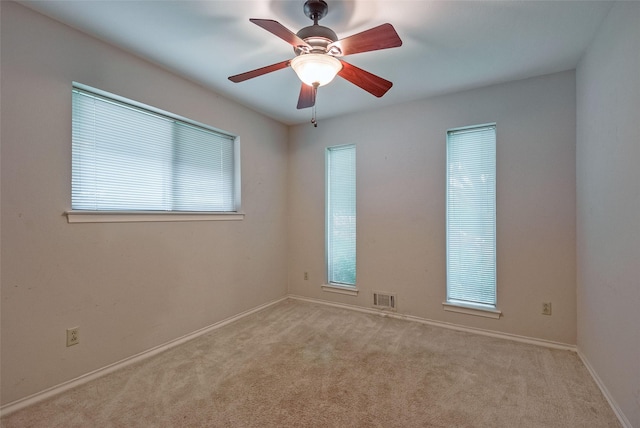 carpeted empty room featuring visible vents, baseboards, and ceiling fan