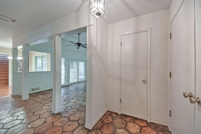 foyer featuring ceiling fan, visible vents, and stone finish floor