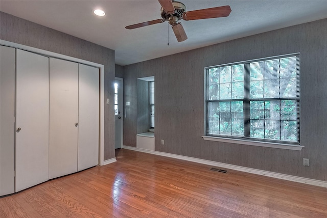 unfurnished bedroom featuring light wood finished floors, a ceiling fan, baseboards, visible vents, and a closet