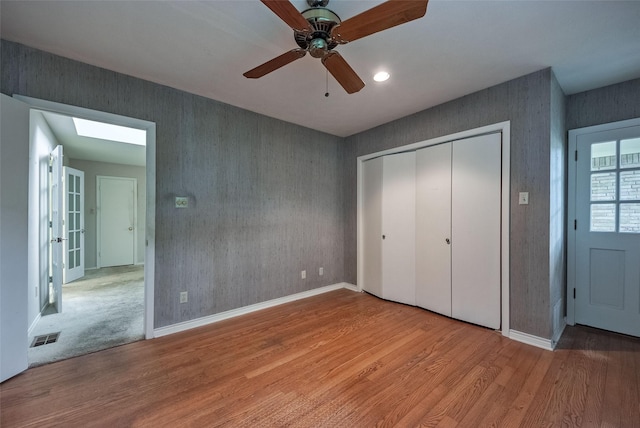 unfurnished bedroom with baseboards, a closet, wood finished floors, and visible vents
