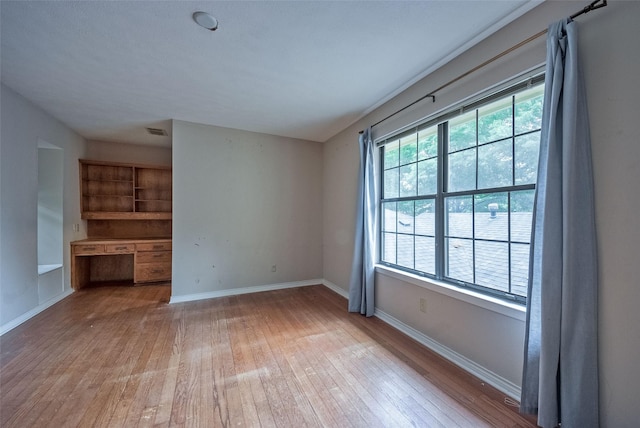 unfurnished living room featuring baseboards, hardwood / wood-style floors, and visible vents