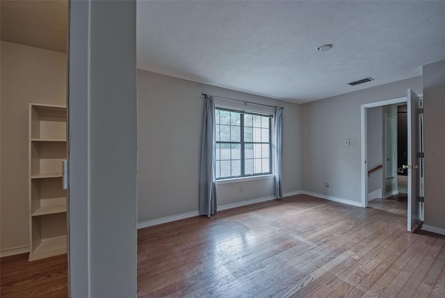 unfurnished room featuring visible vents, baseboards, and wood finished floors