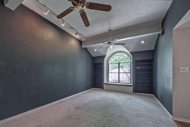 carpeted empty room featuring track lighting, visible vents, a ceiling fan, baseboards, and vaulted ceiling