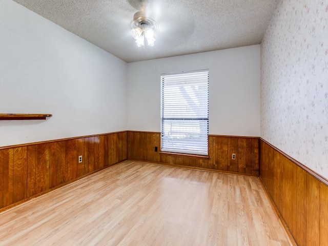 2011 Vicksburg Dr, Sachse, TX 75048 - spare room with a ceiling fan, a textured ceiling, wooden walls, a wainscoted wall, and wood finished floors