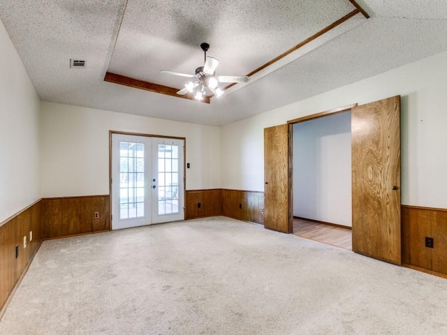 2011 Vicksburg Dr, Sachse, TX 75048 - unfurnished room featuring french doors, visible vents, ceiling fan, wooden walls, and a wainscoted wall