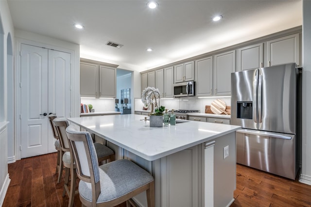 12067 Sunny St, Frisco, TX 75033 - kitchen with appliances with stainless steel finishes, a center island with sink, dark wood finished floors, recessed lighting, and a breakfast bar